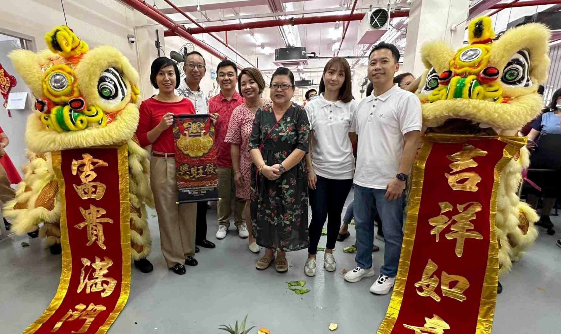 An group photo of Bizlink department heads with our director, Caring Skin staff and lions displaying auspicious words 